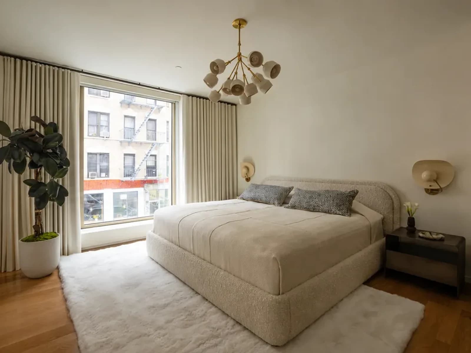 Original bright bedroom with an ivory upholstered bed beside a large window