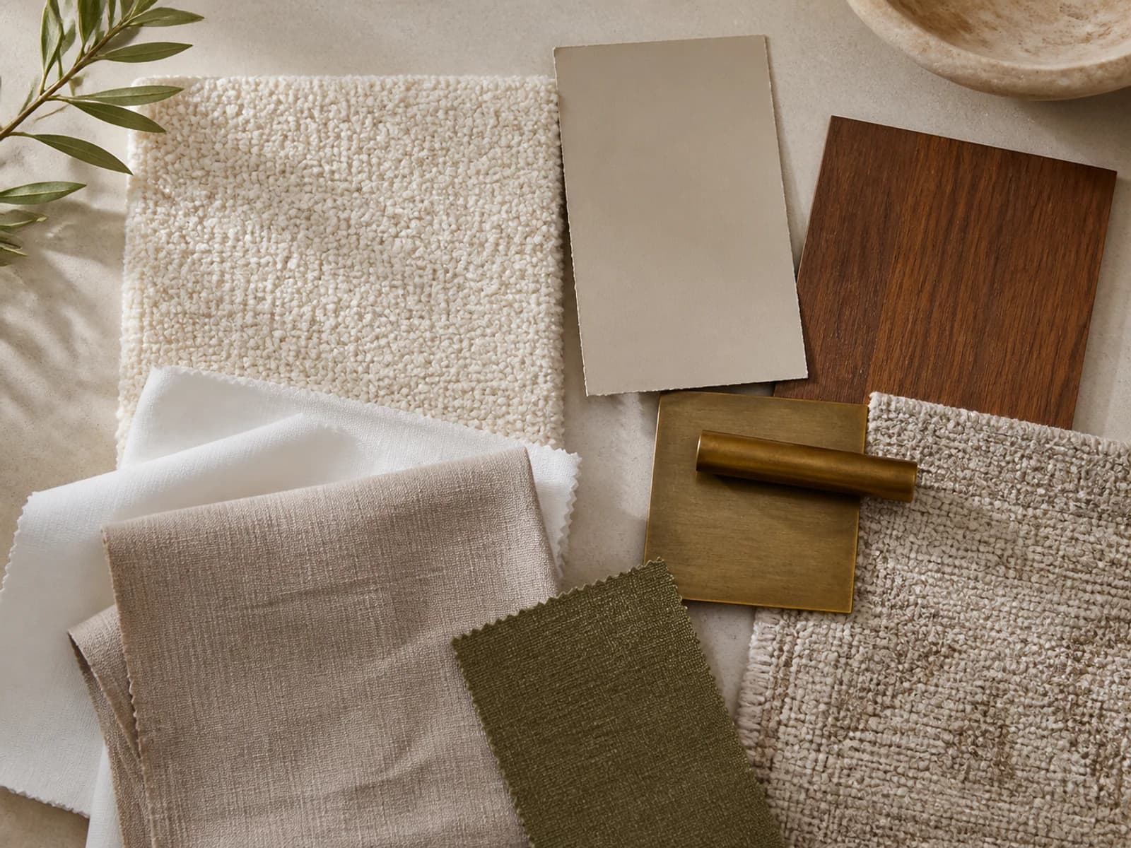 Ivory bouclé, white cotton, taupe linen, oatmeal rug, walnut, brass, olive, and warm-stone bedroom samples
