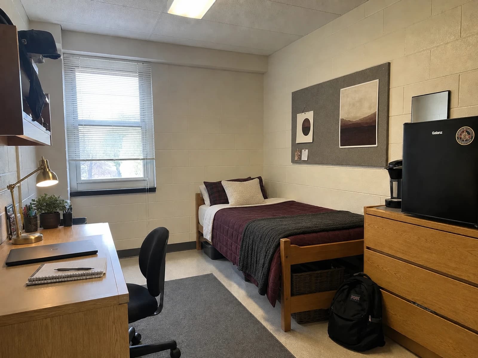 Moody editorial version of the same dorm with deep plum bedding, charcoal texture, warm ivory, and brass tone lighting